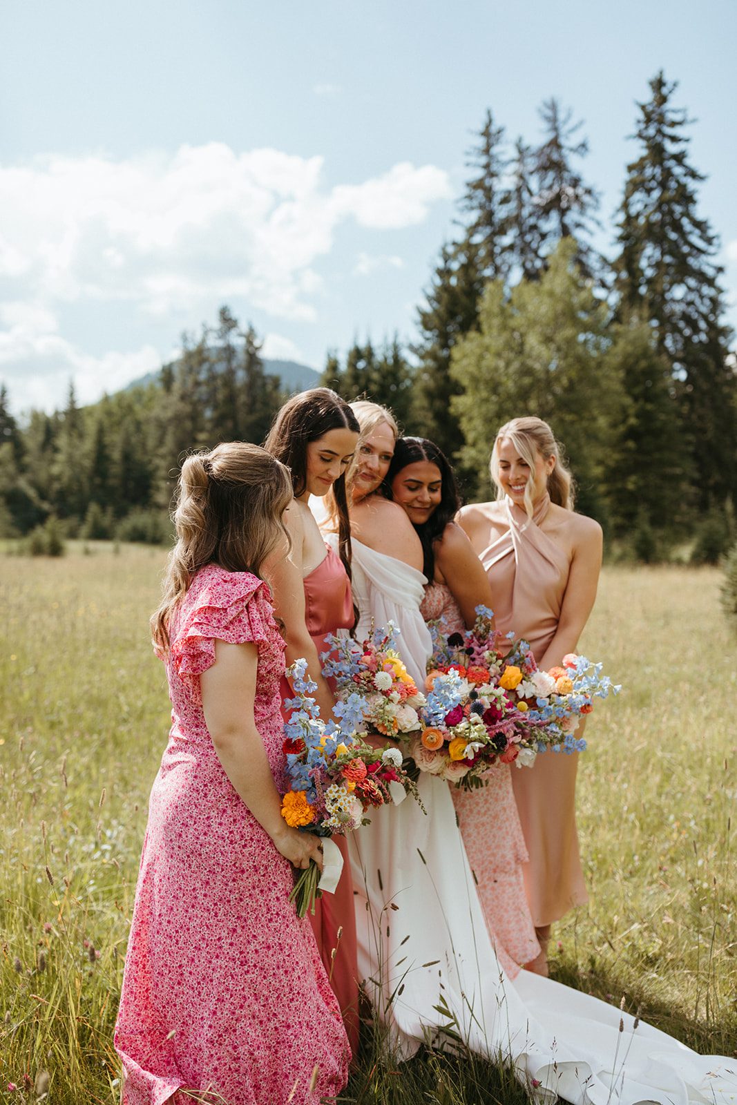 Bridal party in colourful dresses with mountain wildflower bouquets